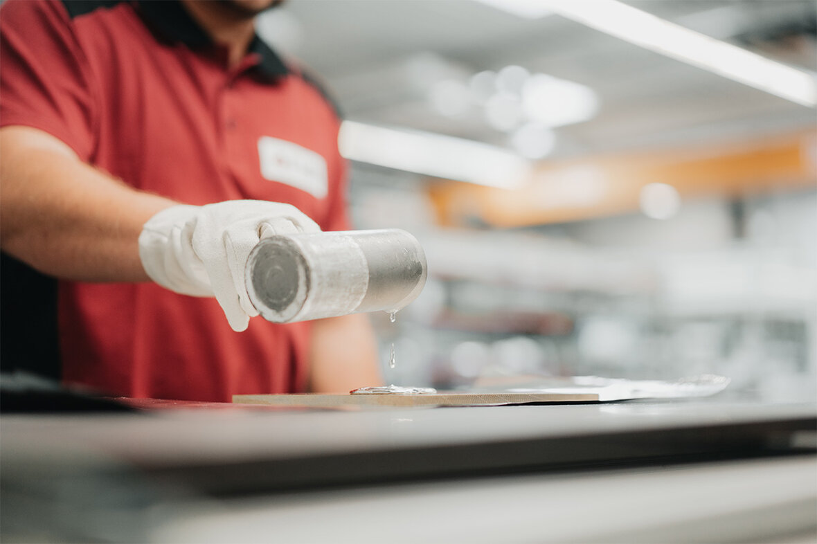 Person gie&szlig;t fl&uuml;ssiges metallisches Material auf eine Tr&auml;gerfl&auml;che zum Bonden von Targets