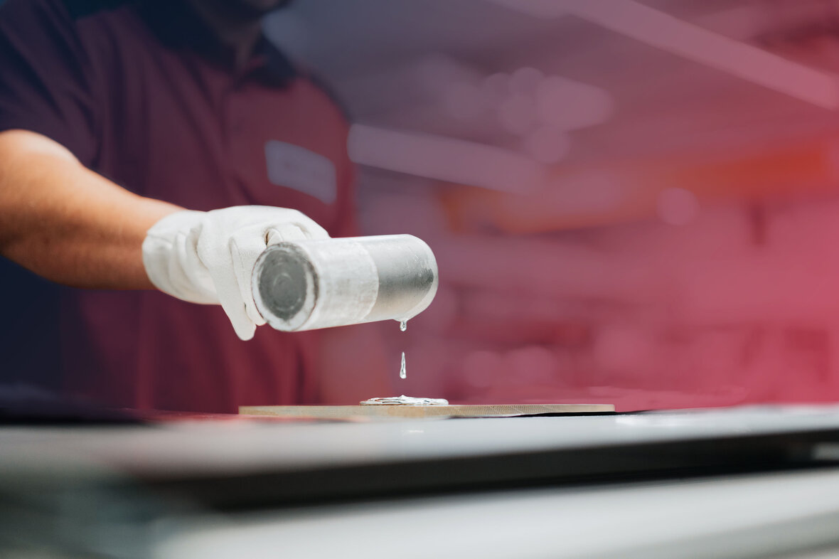 Person gie&szlig;t fl&uuml;ssiges metallisches Material auf eine Tr&auml;gerfl&auml;che zum Bonden von Targets