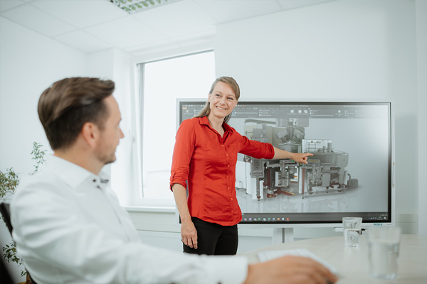 Ingenieurin erl&auml;utert dem Kunden die Funktionsweise der Anlage an einem Monitor