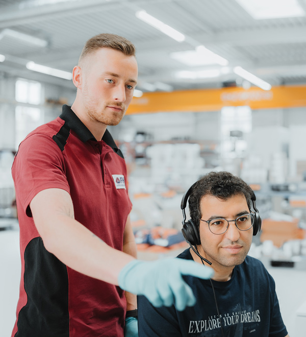 Kundensservicemitarbeiter zeigt einem Konstrukteur etwas an einem Bildschirm