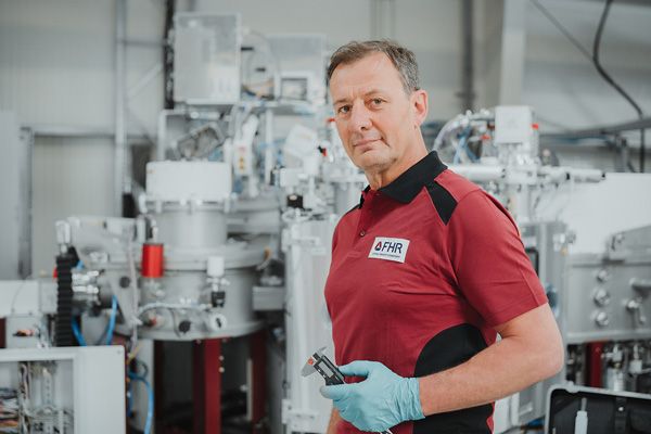 Erfahrener Servicemitarbeiter schaut freundlich und h&auml;lt dabei ein Pr&uuml;finstrument in der Hand